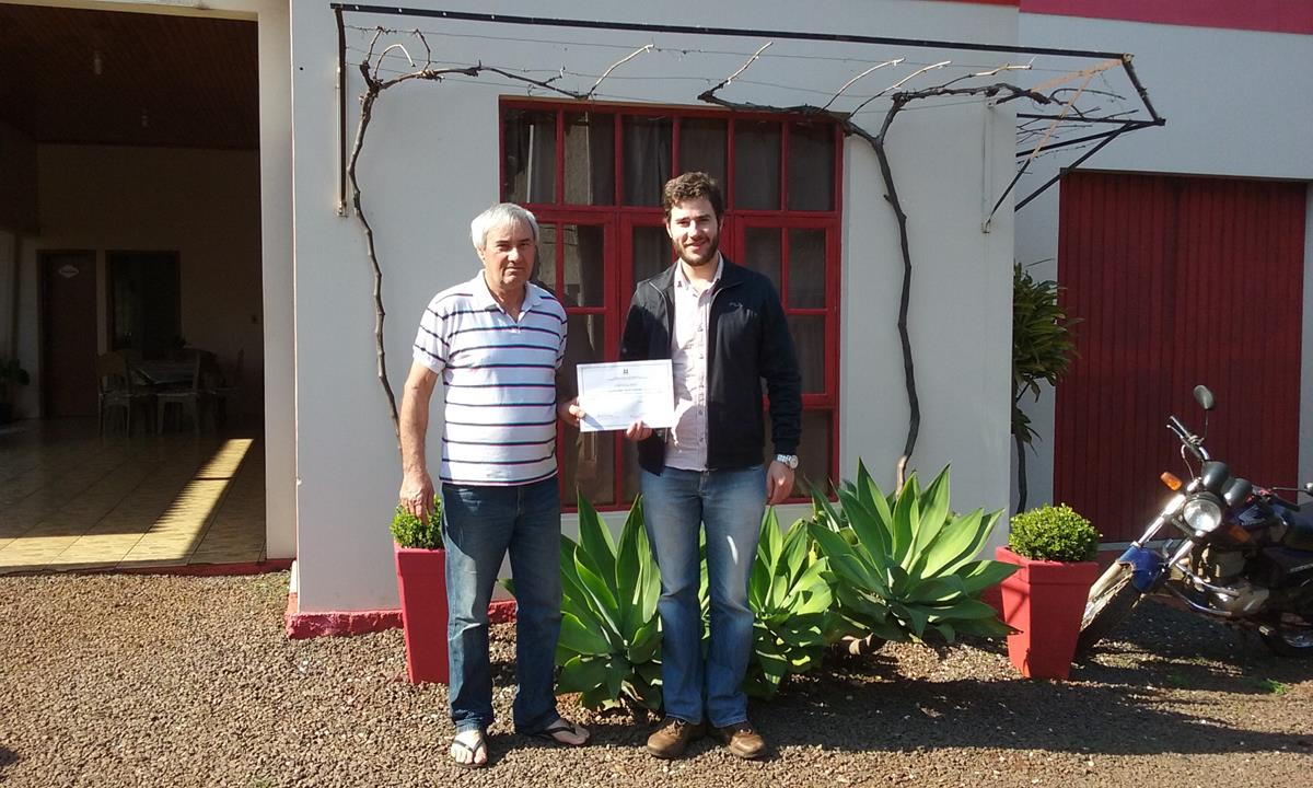 Domênico Weber Chagas entrega o certificado nas mãos de Valdir Colovini