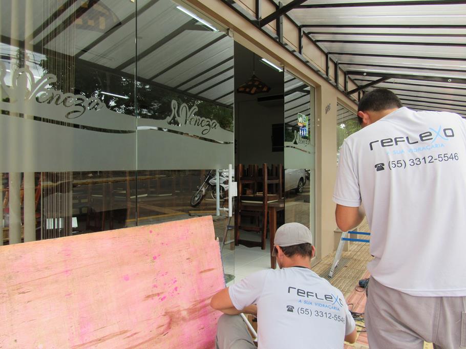 Funcionários da Vidraçaria Reflexo consertam a porta arrombada no Restaurante Veneza